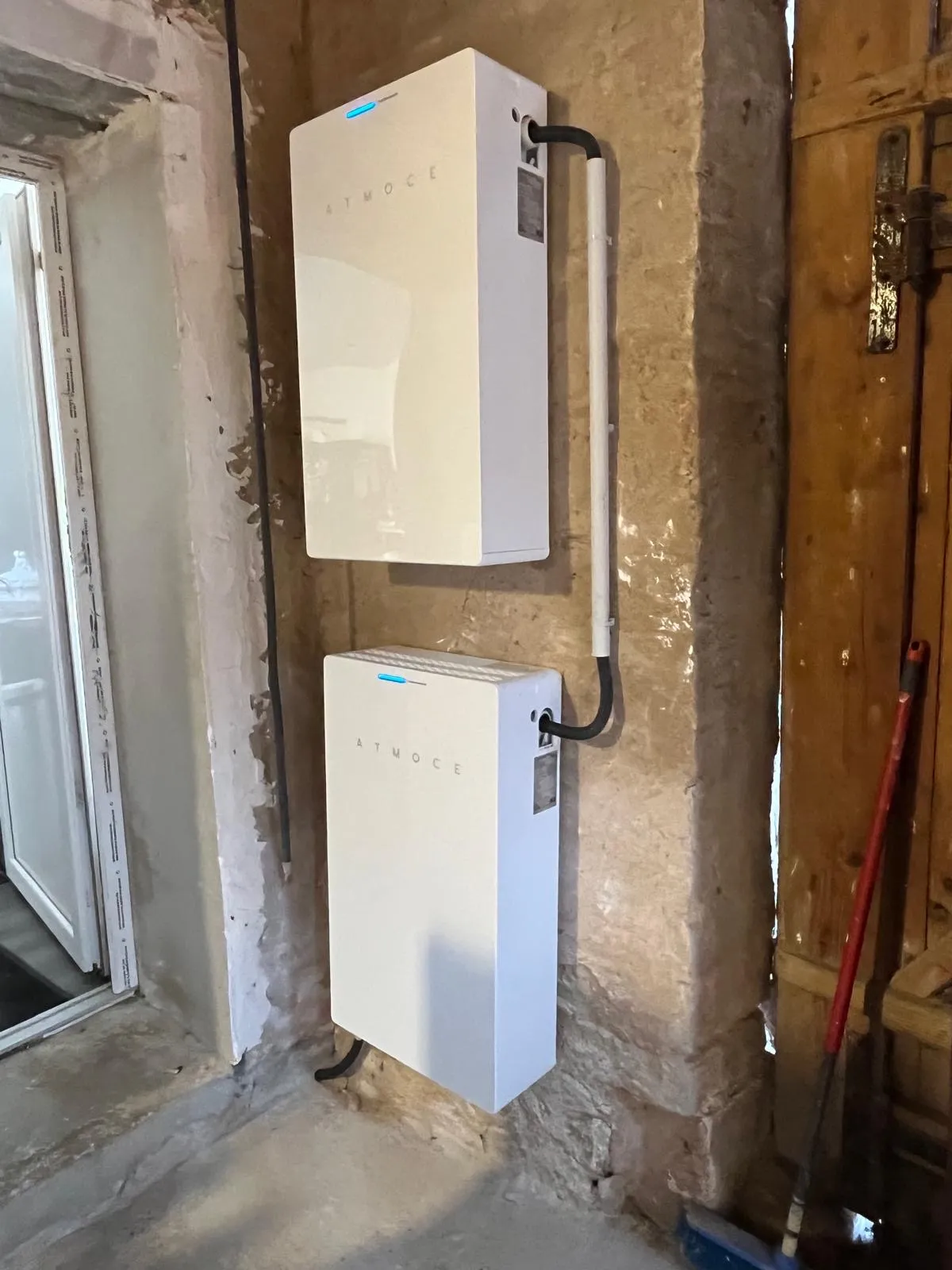 Deux batteries de stockage Atmoce superposées, installées par ISL CLIM sur un mur en pierre