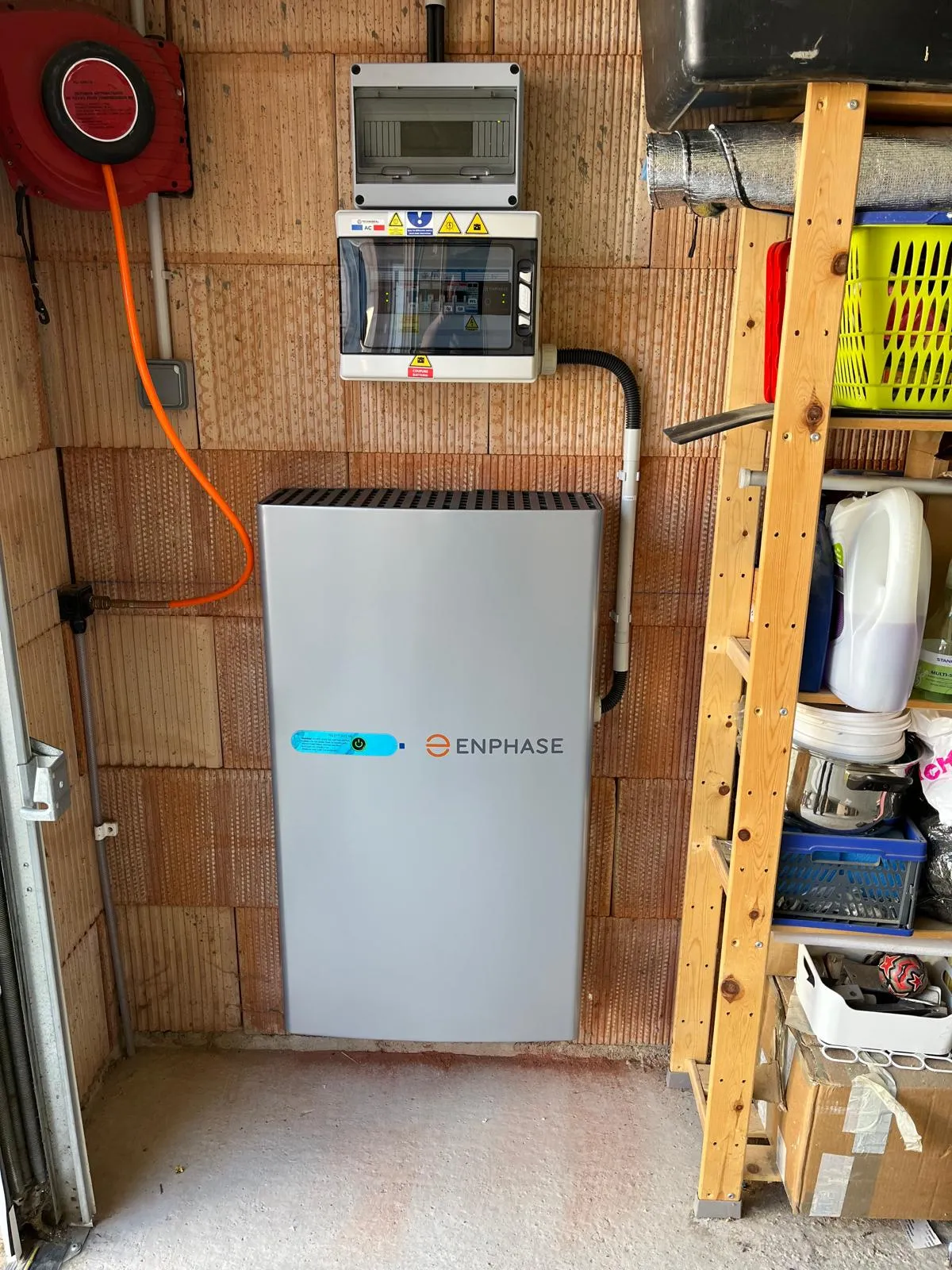 Batterie de stockage Enphase installée par ISL CLIM contre le mur d’un garage, avec coffret de protection