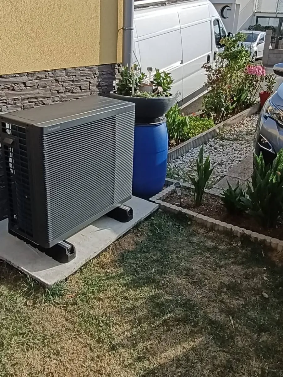 Unité extérieure de pompe à chaleur Panasonic posée sur socle par ISL CLIM au pied d’une façade