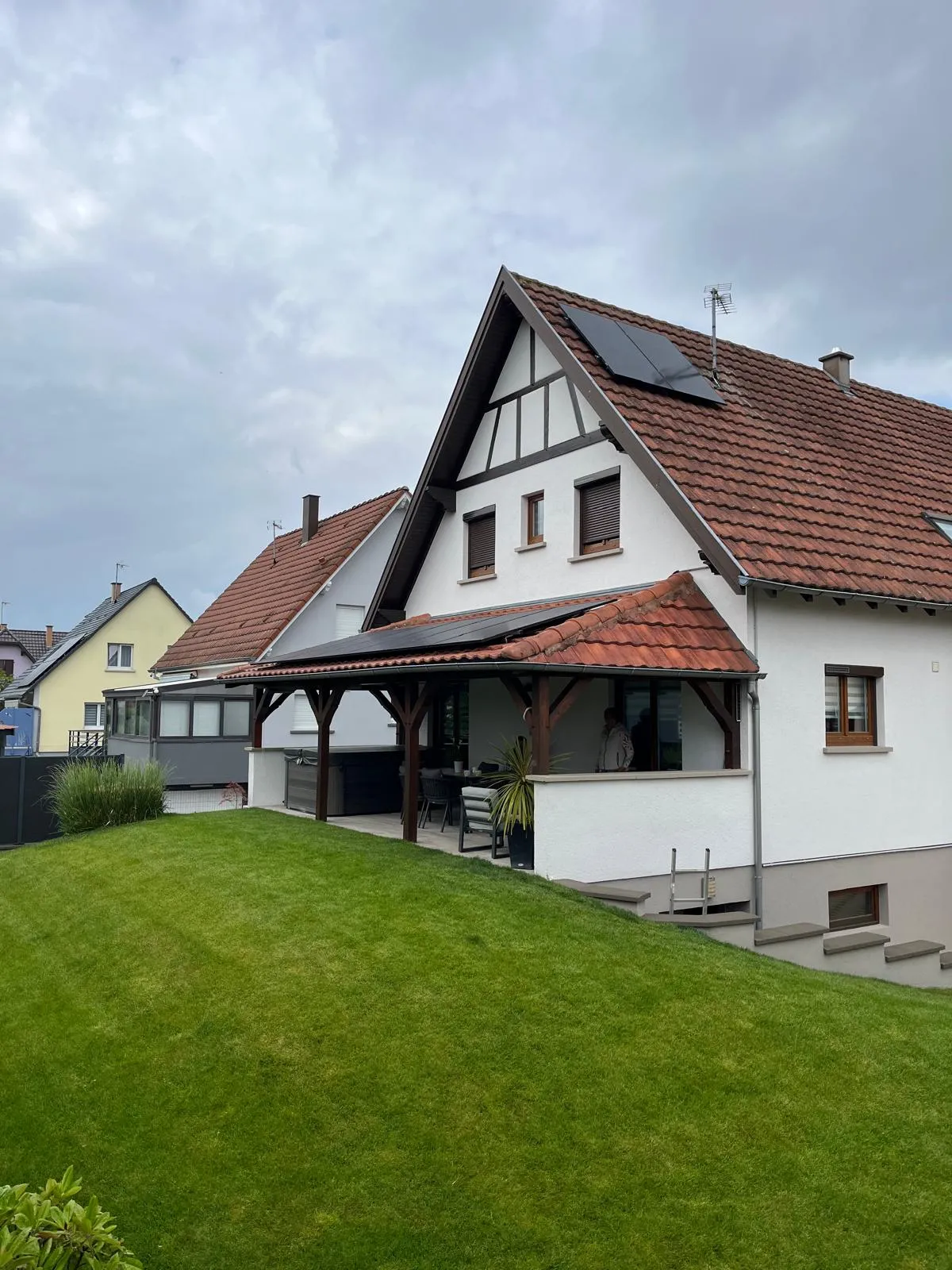 Panneaux photovoltaïques noirs installés par ISL CLIM sur la toiture d’une maison alsacienne avec pergola