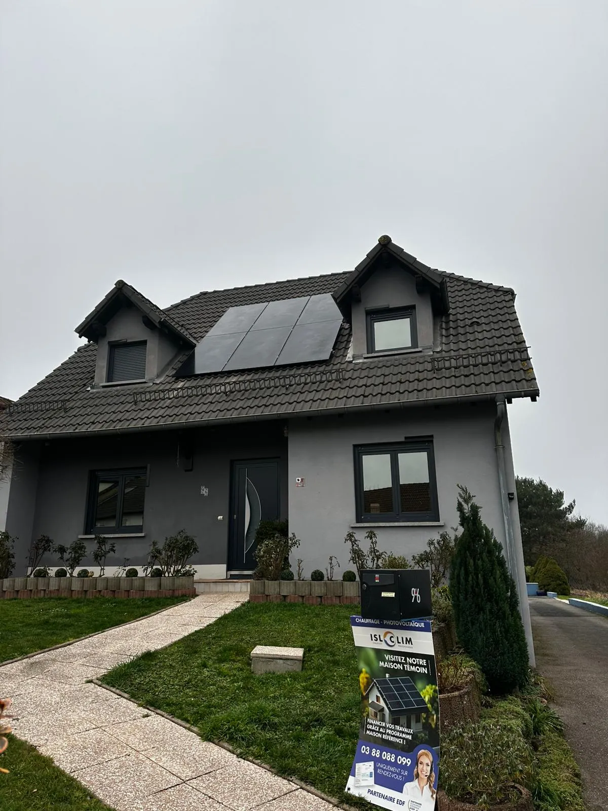 Maison grise équipée de panneaux photovoltaïques installés par ISL CLIM entre deux lucarnes